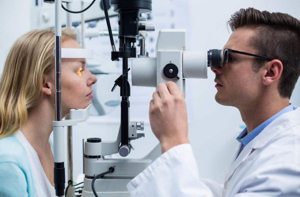 A male optometrist using a medical device to examine the eyes of a female patient and look for potential eye problems.