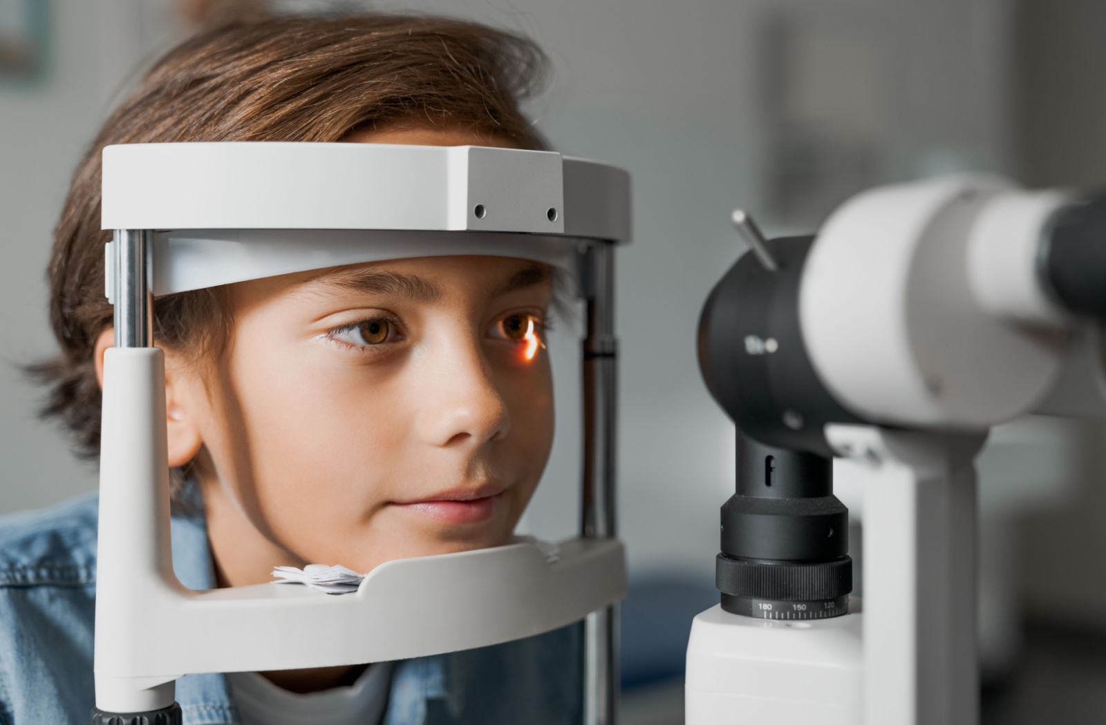 Close-up of a young boy looking into a machine that tests his vision