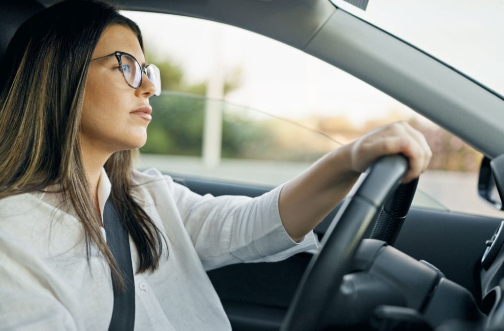 A woman wearing prescription glasses to correct her astigmatism confidently drives her car