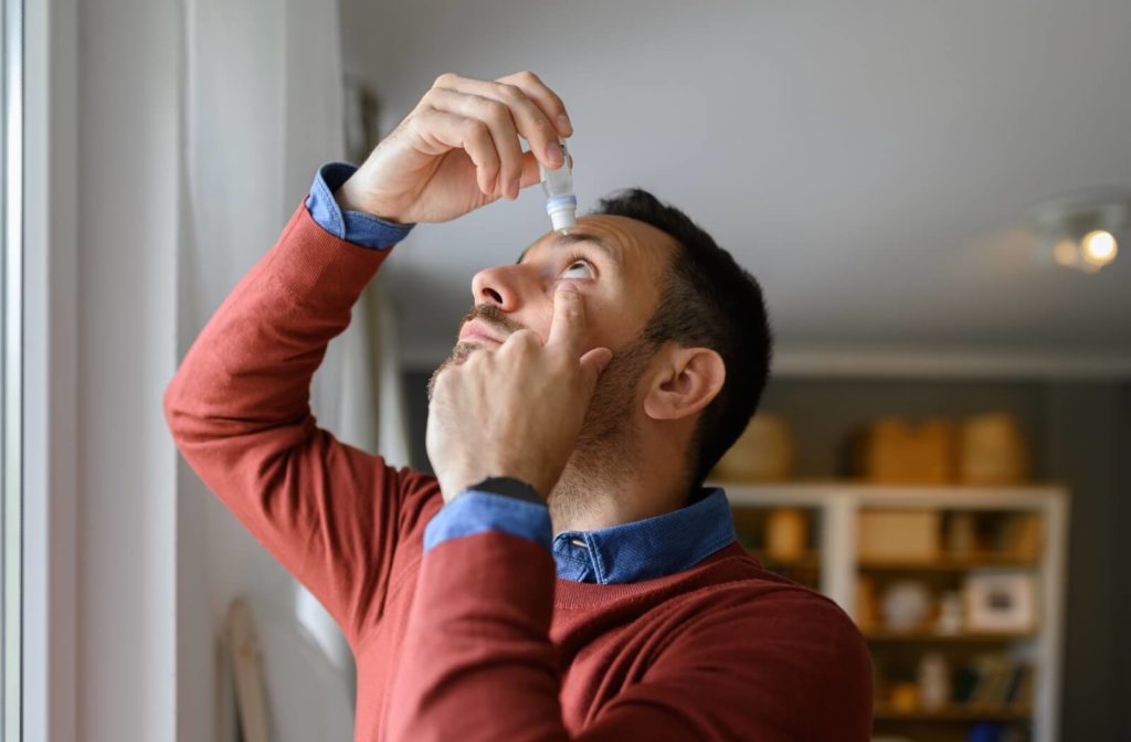 A person applies eye drops to their eye, to find relief from allergic conjunctivitis.