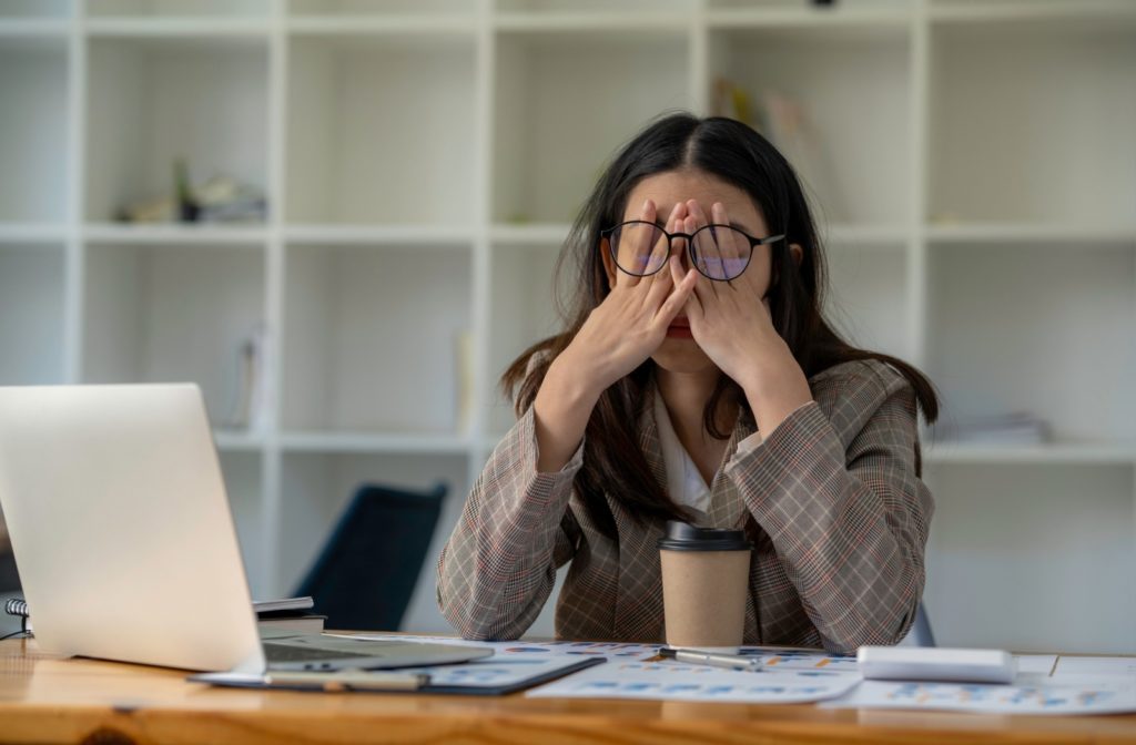 A professional at work covers their eyes due to stress and anxiety.