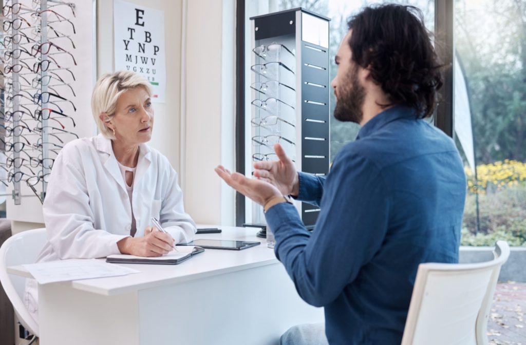 A patient explains their symptoms to an optometrist during an eye exam.