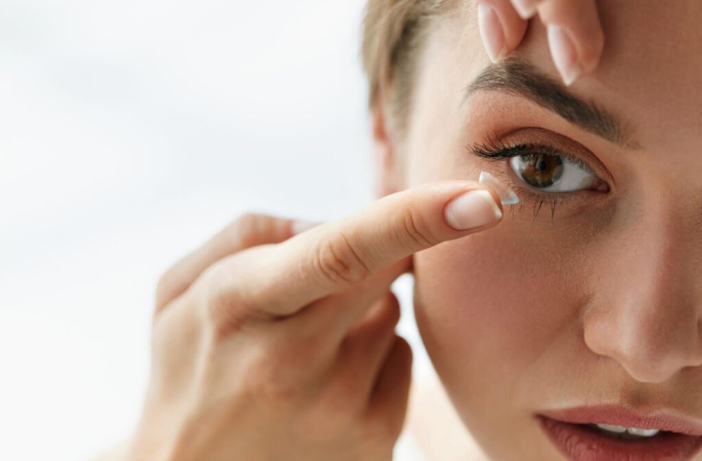a close up of a person inserting a contact lens into their eye.